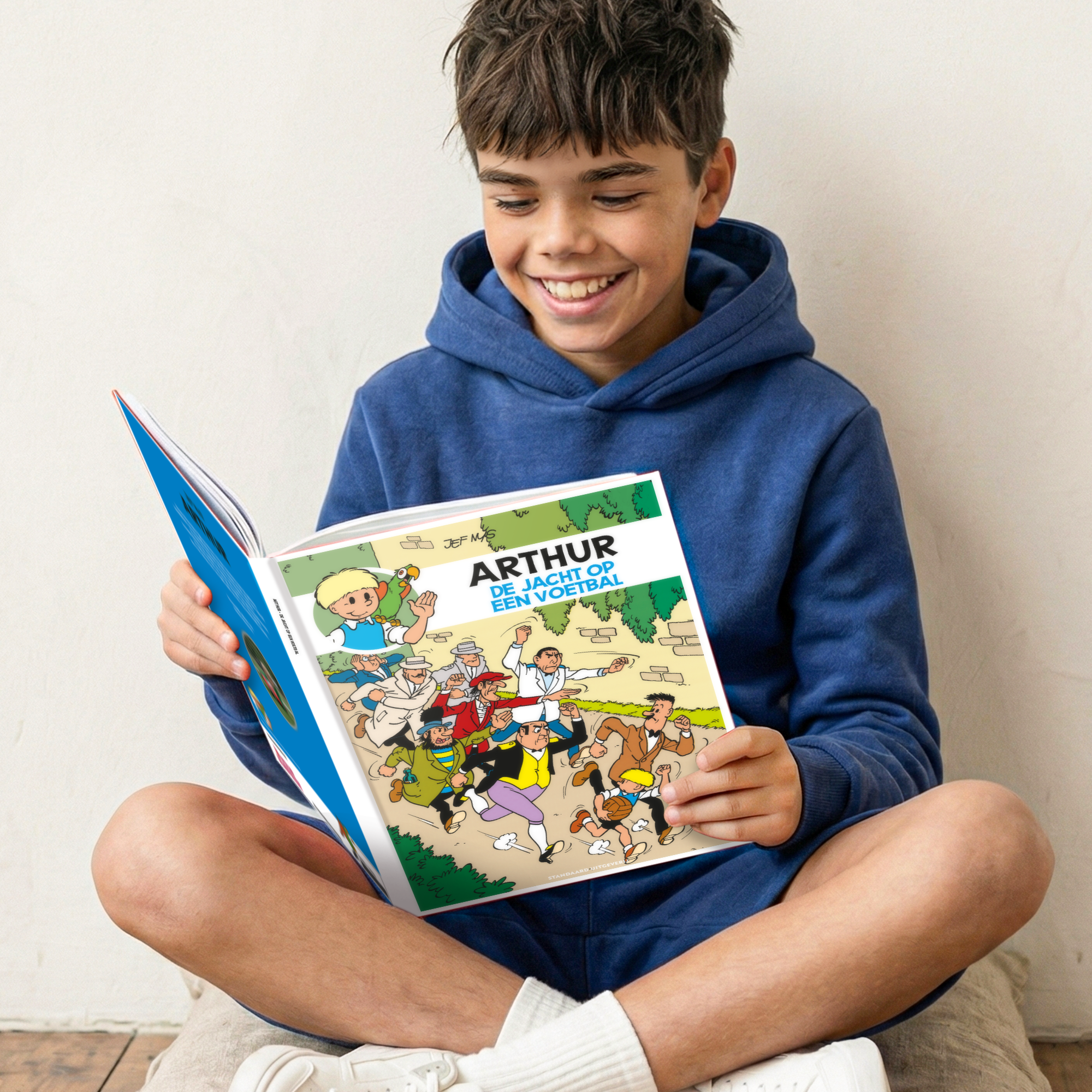 Blije jongen leest een persoonlijk stripboek - Jommeke 'De jacht op een voetbal' (Hardcover) waarbij zijn eigen naam Arthur als gepersonaliseerde titel is gedrukt.