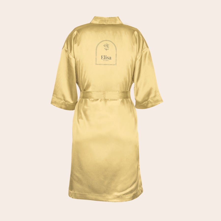 Quimono personalizado Quimono dourado personalizado com o nome Elisa impresso em preto, com um desenho floral no topo.