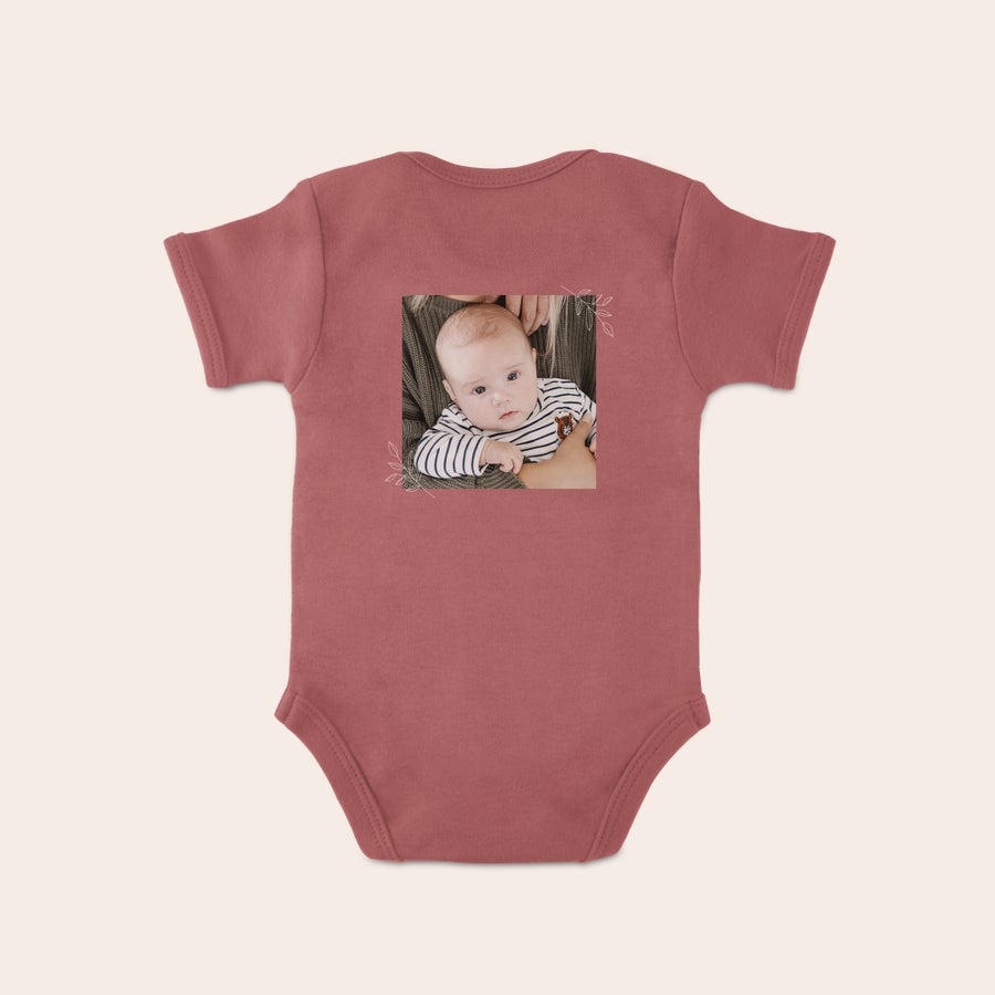 Vauvan bodysuit Vauvan potkupuku, jossa on painatus suloisesta vauvasta valkoisen lehden muotoilun ympäröimänä