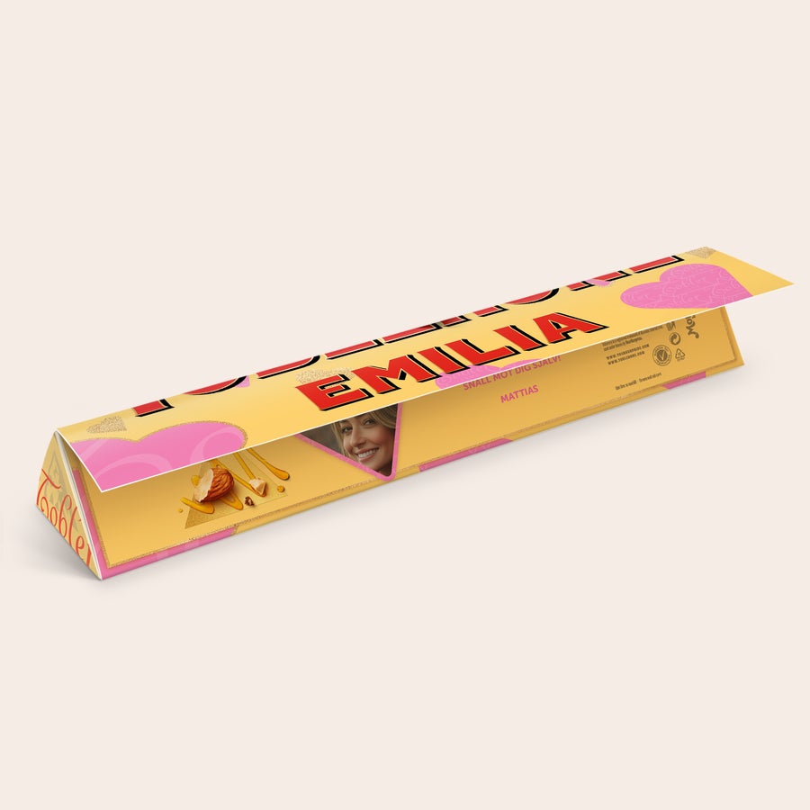 Toblerone med namn och foto Personlig Toblerone med namn Emilia och foto av en kvinna, tryckt på förpackningen. Skapa din egen Toblerone med namn och foto.