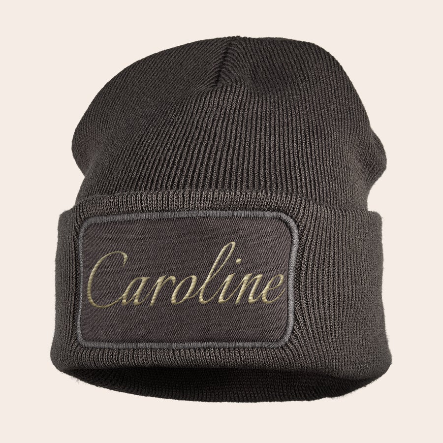 Broderad hatt Mörkgrå mössa broderad med namnet Caroline i ljusbeige tråd. Håll de små öronen snygga och varma med en cool mössa med broderat namn!