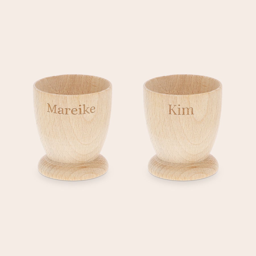 Eierbecher personalisiert Zwei personalisierte Eierbecher aus hellem Buchenholz, graviert mit den Namen "Mareike" und "Kim" für unvergessliche Frühstücksmomente.