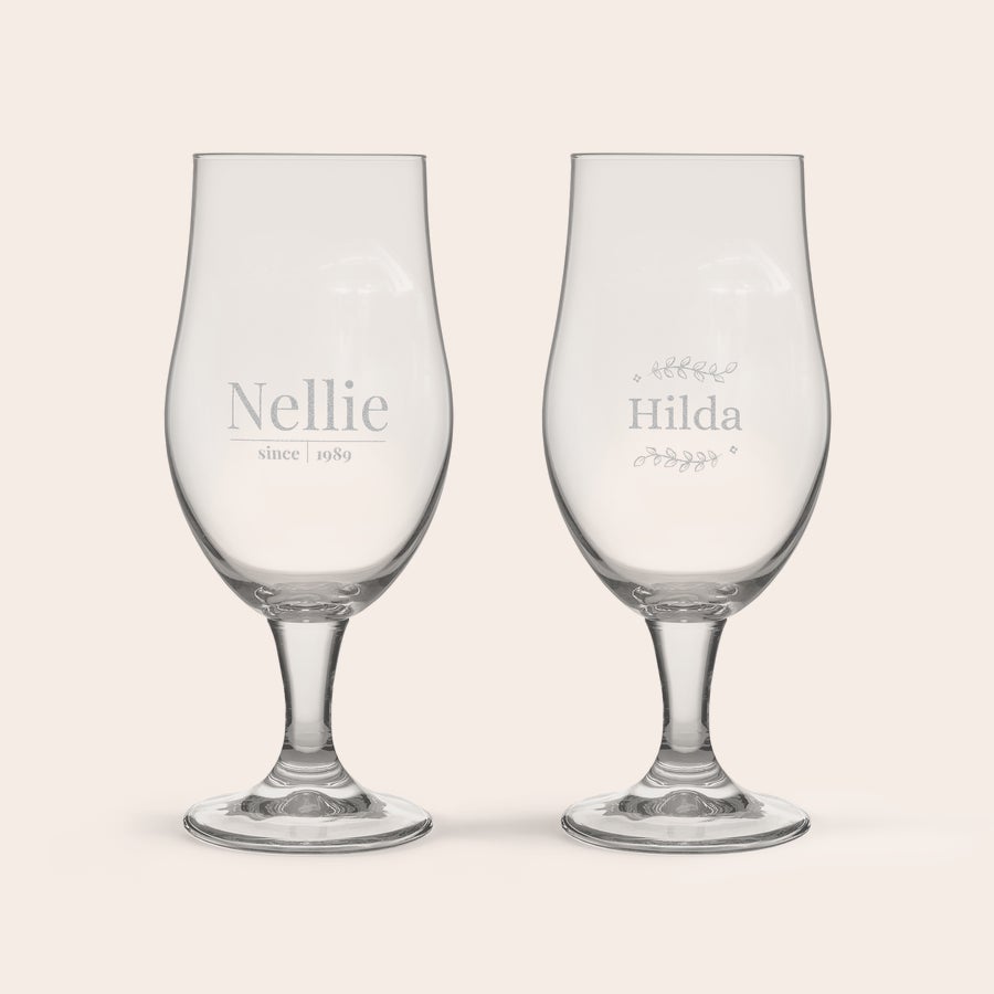 Graverat Pina Colada cocktailglas Två graverade pina colada glas, det första med namnet "Nellie since 1989" och det andra med namnet "Hilda" omgivet av blad.