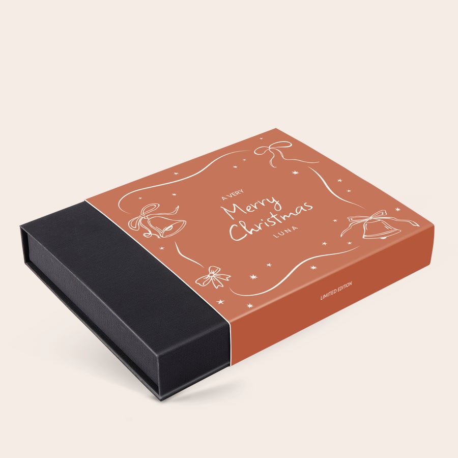 Cutie cadou de ciocolată de lux - Crăciun Cutie bomboane de ciocolată de Crăciun personalizate, cu text "Merry Christmas Luna" imprimat, clopoței, funde și steluțe albe pe fond portocaliu, și cutie neagră.