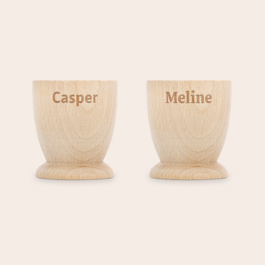 Personifierad äggkopp Personliga äggkoppar i bokträ graverade med namnen Casper och Meline för en minnesvärd frukost.