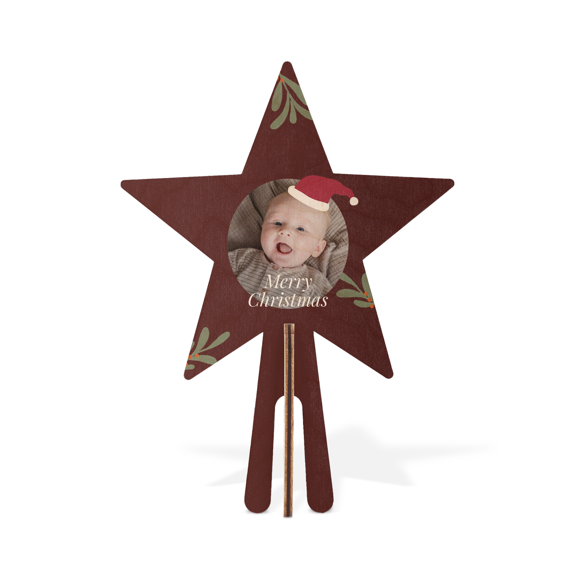 Rödbrun julstjärna i trä med tryckt babyfoto, texten Merry Christmas och gröna blad. Skräddarsydd trätopp.