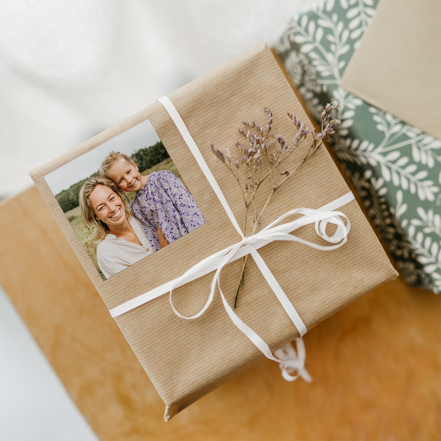 Pegatinas con foto Regalo envuelto en papel craft con lazo blanco, decorado con pegatinas personalizadas impresas con la foto de una madre y su hija.