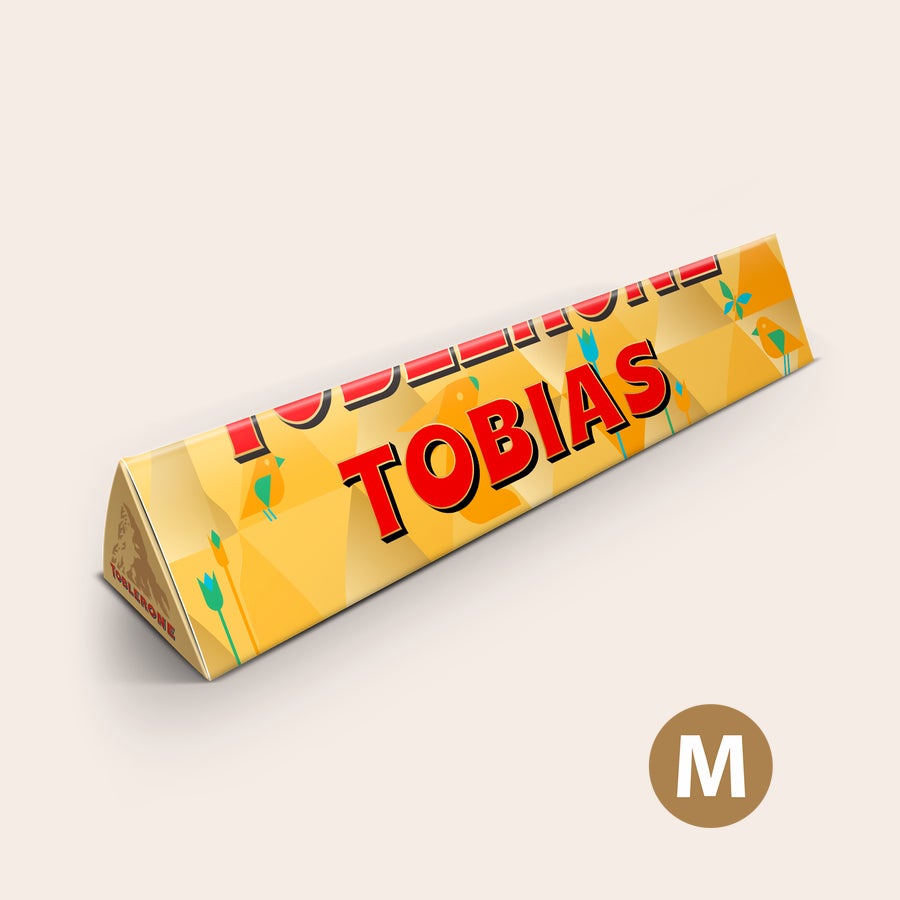Toblerone chokolade med navn - Påske Personlig Toblerone i påskedesign med navnet Tobias, trykt med et påsketema af kyllinger og blomster. Ønsk dine nærmeste en rigtig god Påske.