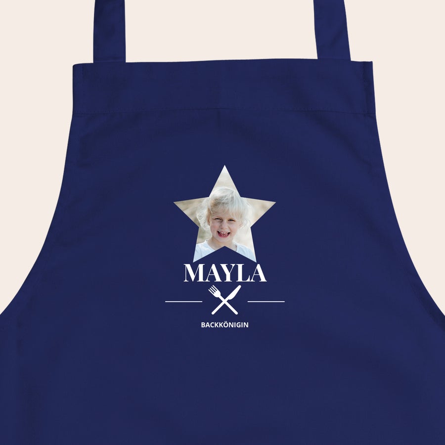 Kinderschürze personalisiert Dunkelblaue Kinderschürze mit dem aufgedruckten Foto eines Mädchens in einem Stern, dem Namen Mayla und dem Text Backkönigin.