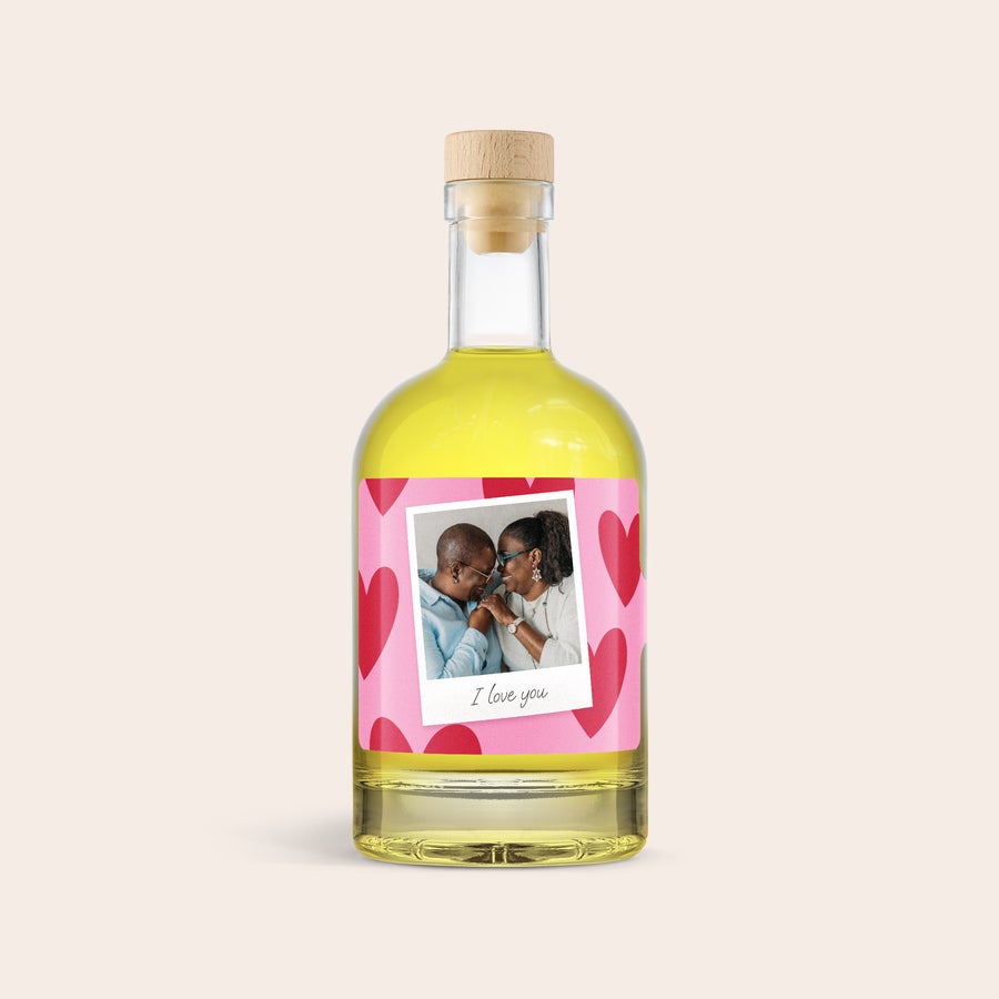 Limoncello personalizzato - YourSurprise Bottiglia di limoncello con etichetta rosa personalizzata con foto di coppia e testo I love you, su fondo a cuori rossi
