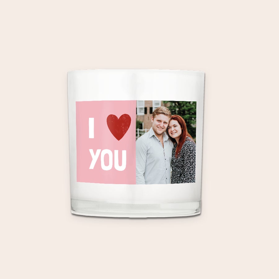 Ljus i glas Ett personaliserat ljus med tryckt bild på ett par och texten I love you i rosa på en vit glashållare