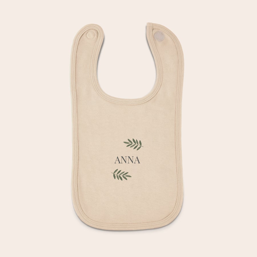 Hagesmæk Personlig hagesmæk i beige med navnet ANNA og bladmotiver, trykt med valgfri tekst og designs.