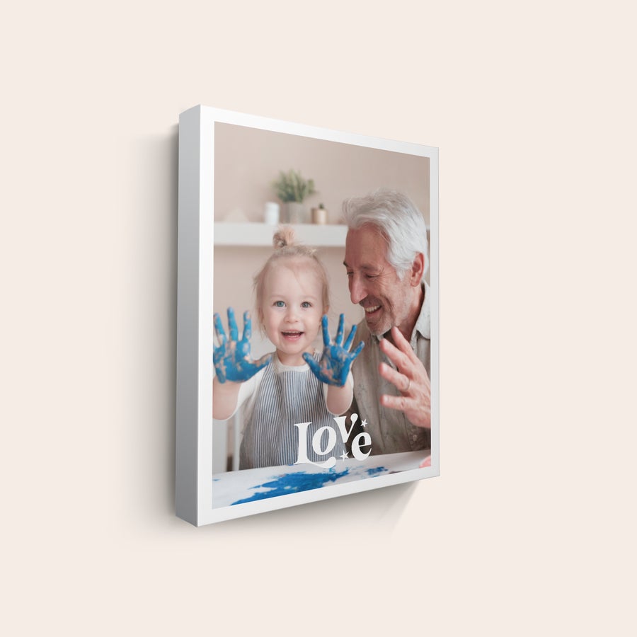 Canvas-taulu Canvas-taulu, jossa on kuva hymyilevästä tytöstä ja miehestä. Tytön kädet ovat sinisen maalin peitossa, ja taulussa lukee "Love". Voit tulosta kauneimmat kuvasi canvas-tauluksi.