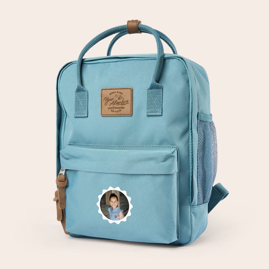 Personaliziran otroški nahrbtnik Svetlo moder personaliziran nahrbtnik s fotografijo otroka natisnjeno na sprednji žep.