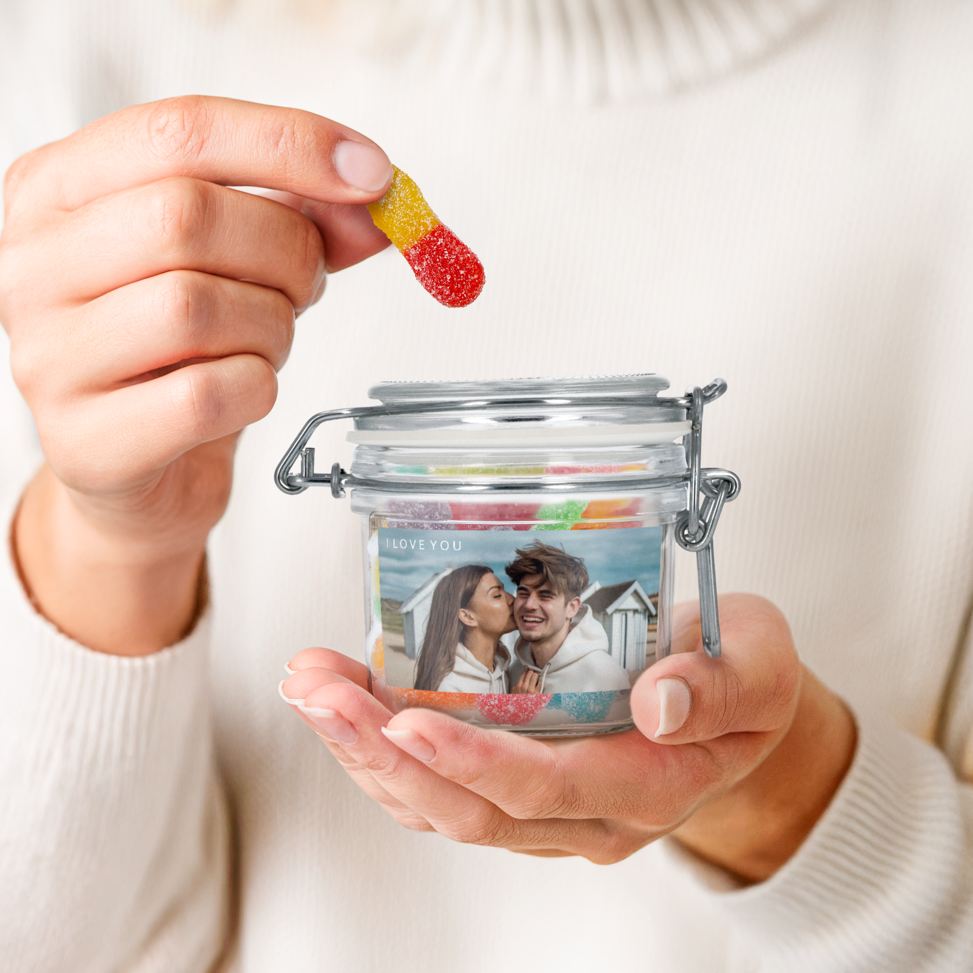 Hands holding a personalised sweet jar with sour sticks, printed with a photo of a couple and I LOVE YOU text