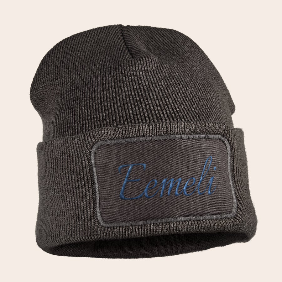 Pipo nimellä - Brodeeraus Ruskea pipo, jossa on brodeerattu "Eemeli"-nimi sinisellä langalla ommellussa kangasmerkissä.