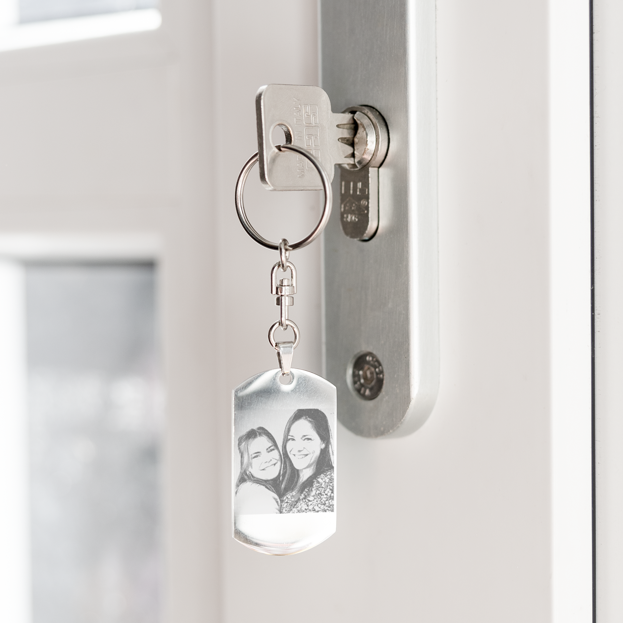 Personalized photo keyring engraved with two smiling women hanging from a door key