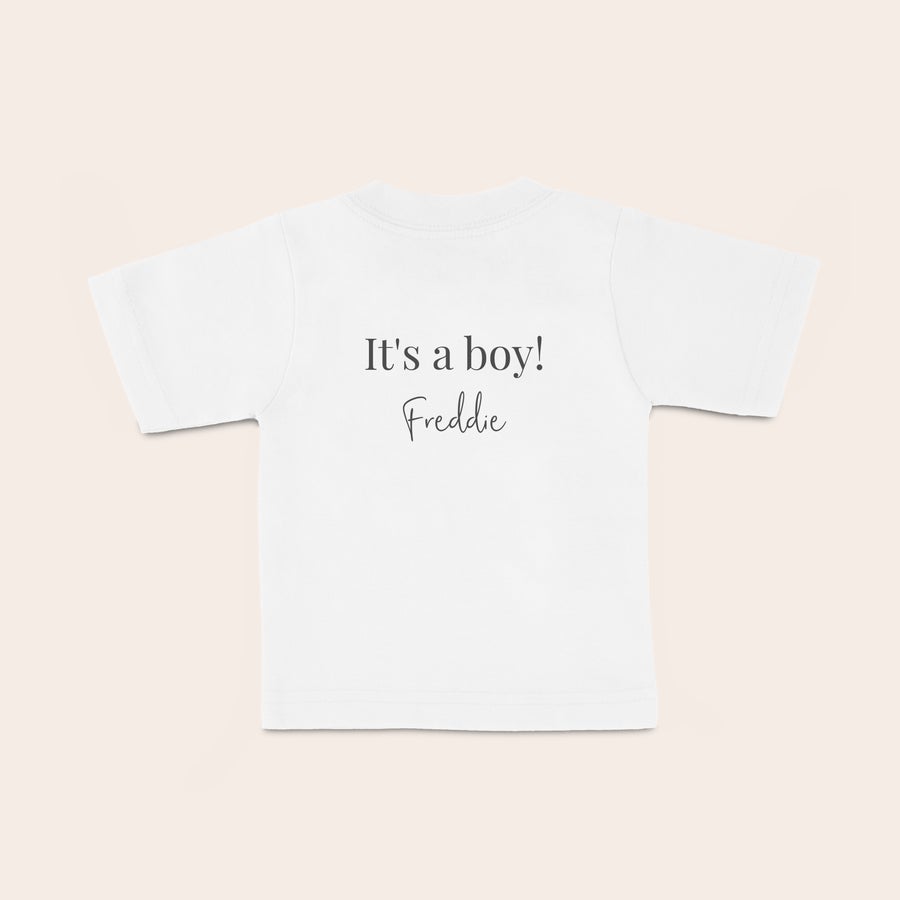 Vauvan T-paita Vauvan tyyli on taattu valkoisella paidalla, johon on painatettu teksti "It's a boy! Freddie"