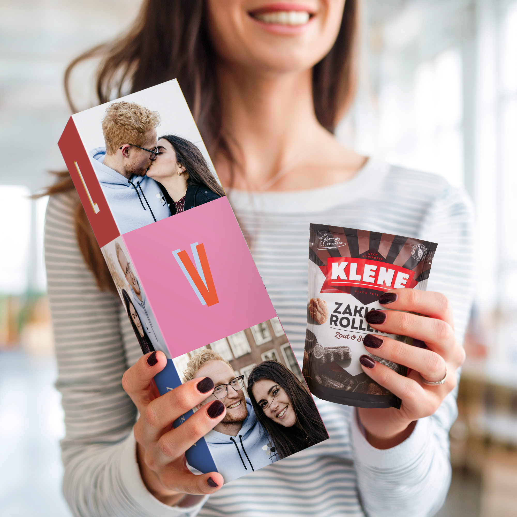 Een vrouw toont een gepersonaliseerd snoeppakket boordevol drop met twee eigen foto's en een grote letter V, naast een zak Klene muntdrop.