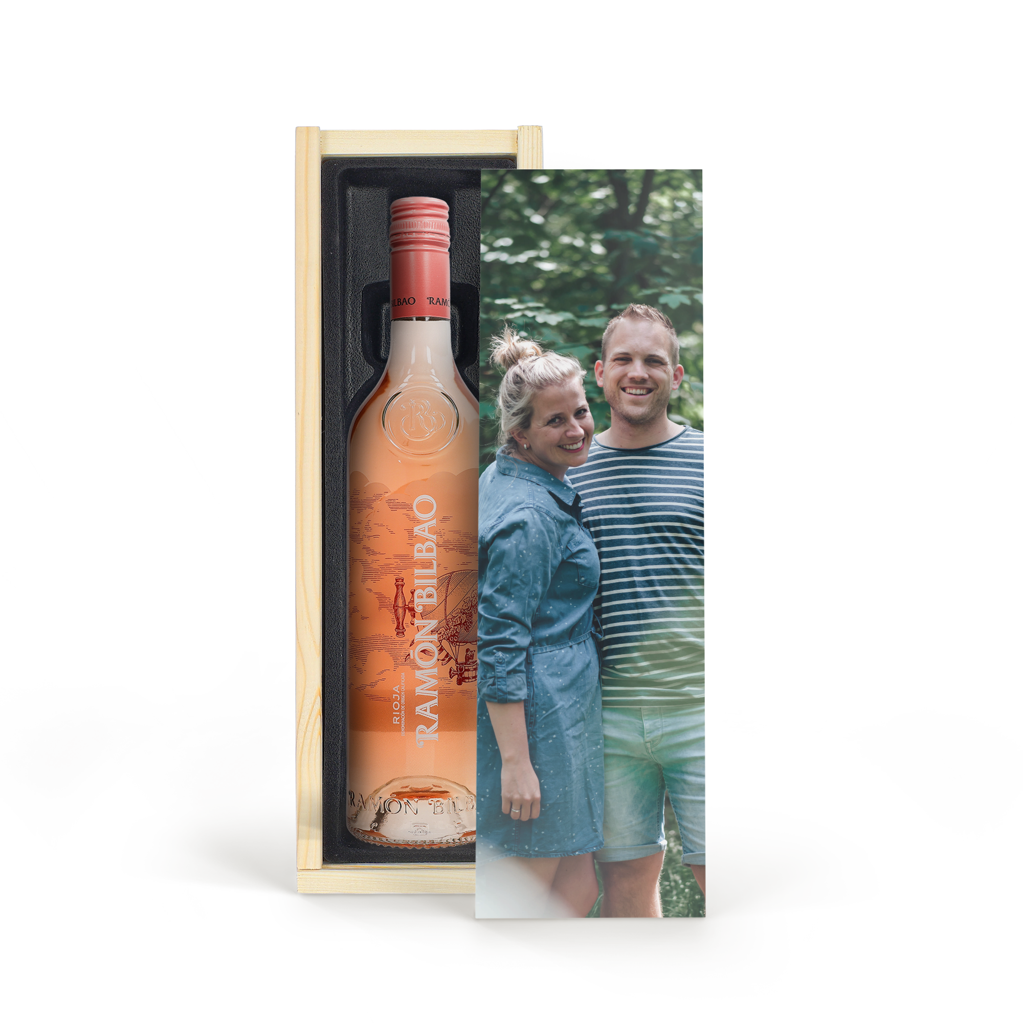 Egy üveg Ramon Bilbao rosé egy luxus, személyre szabott tokban, amivel meglephetsz valakit, mellette mosolygó pár.
