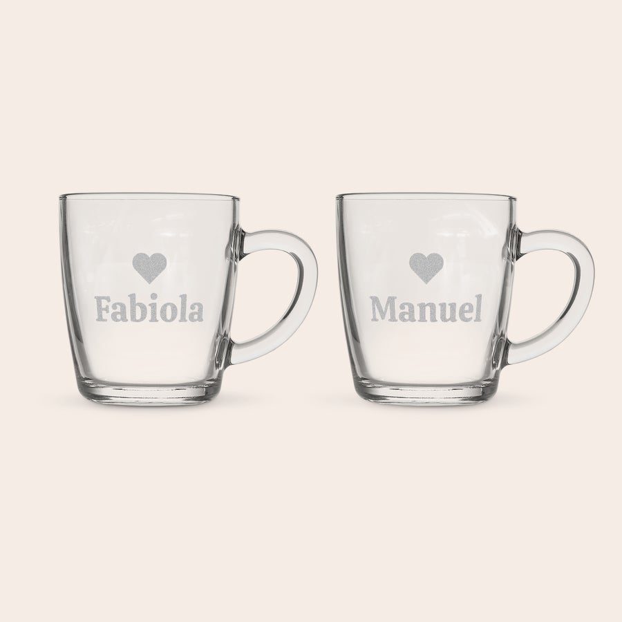 Theglas Två graverade glasmuggar med namnen Fabiola och Manuel med ett hjärta ovanför. Njut av ditt te i en graverad glasmugg!