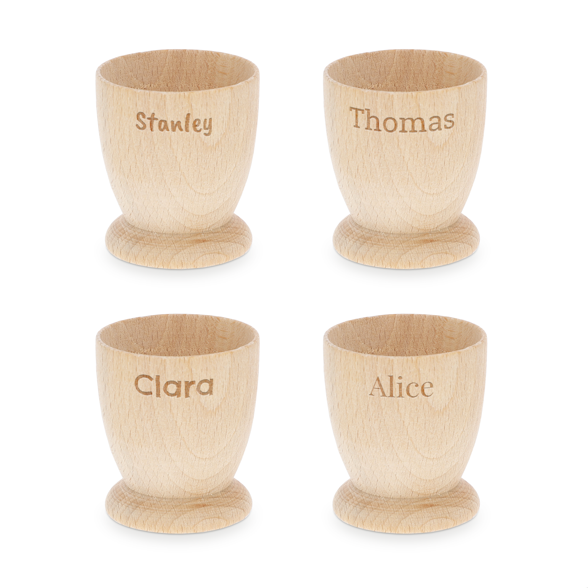Quattro portauova personalizzati in legno chiaro con nomi incisi, "Stanley", "Thomas", "Clara" e "Alice" per una colazione memorabile