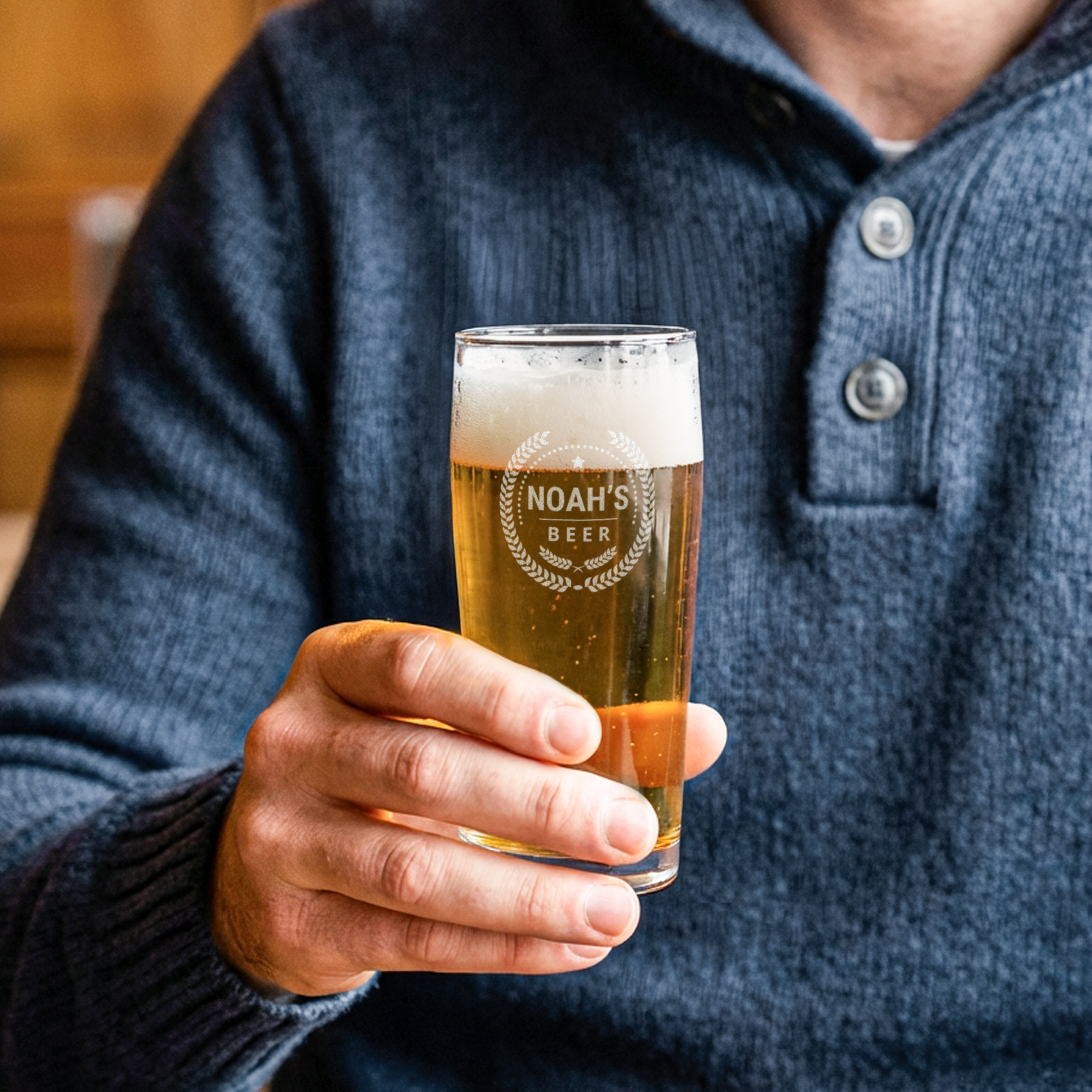 Gravert mini ølglass - 1 stk. holdt av en mann, personliggjort med teksten Noah's Beer og et laurbærkransdesign.