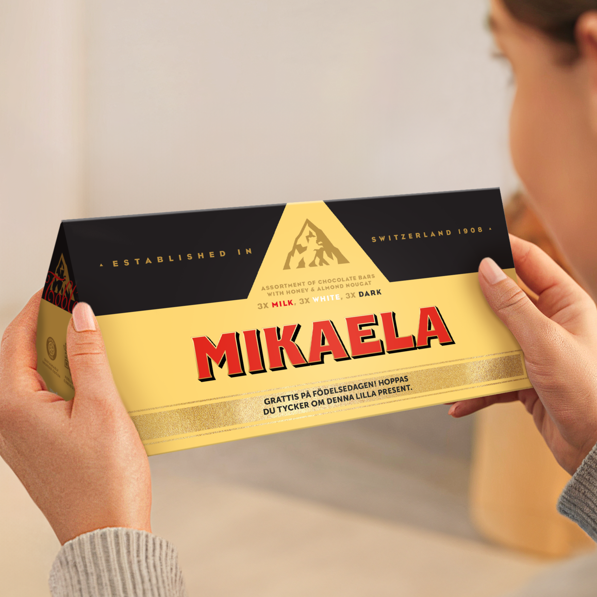 Personlig XL Toblerone Selection chokladkaka med namnet Mikaela och ett grattismeddelande, tryckt på omslaget.