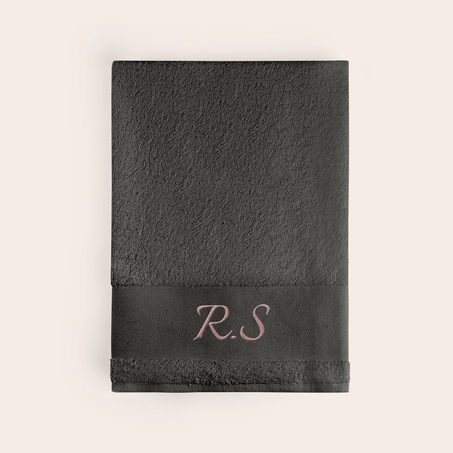 Toalla de baño con texto Toalla de baño personalizada antracita con las iniciales "R.S" bordadas en rosa claro.