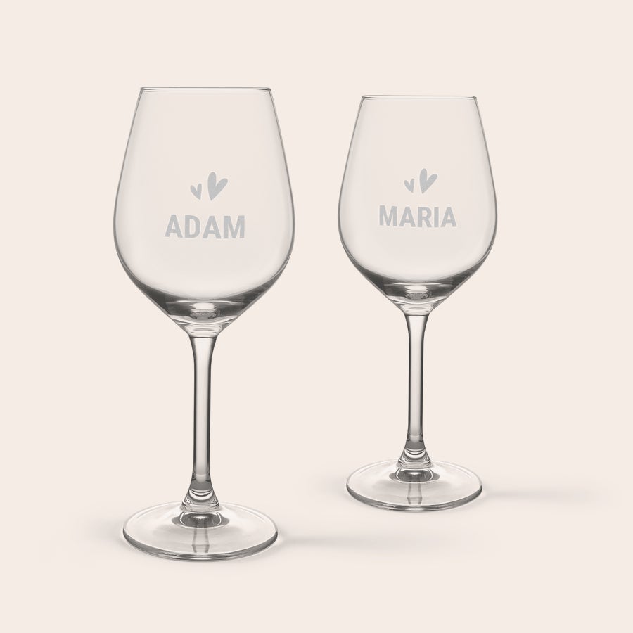 Personalised wine & snacks gift set Two personalized wine glasses, engraved with "Adam" and "Maria" and small heart designs, part of a personalised wine & snacks gift set.