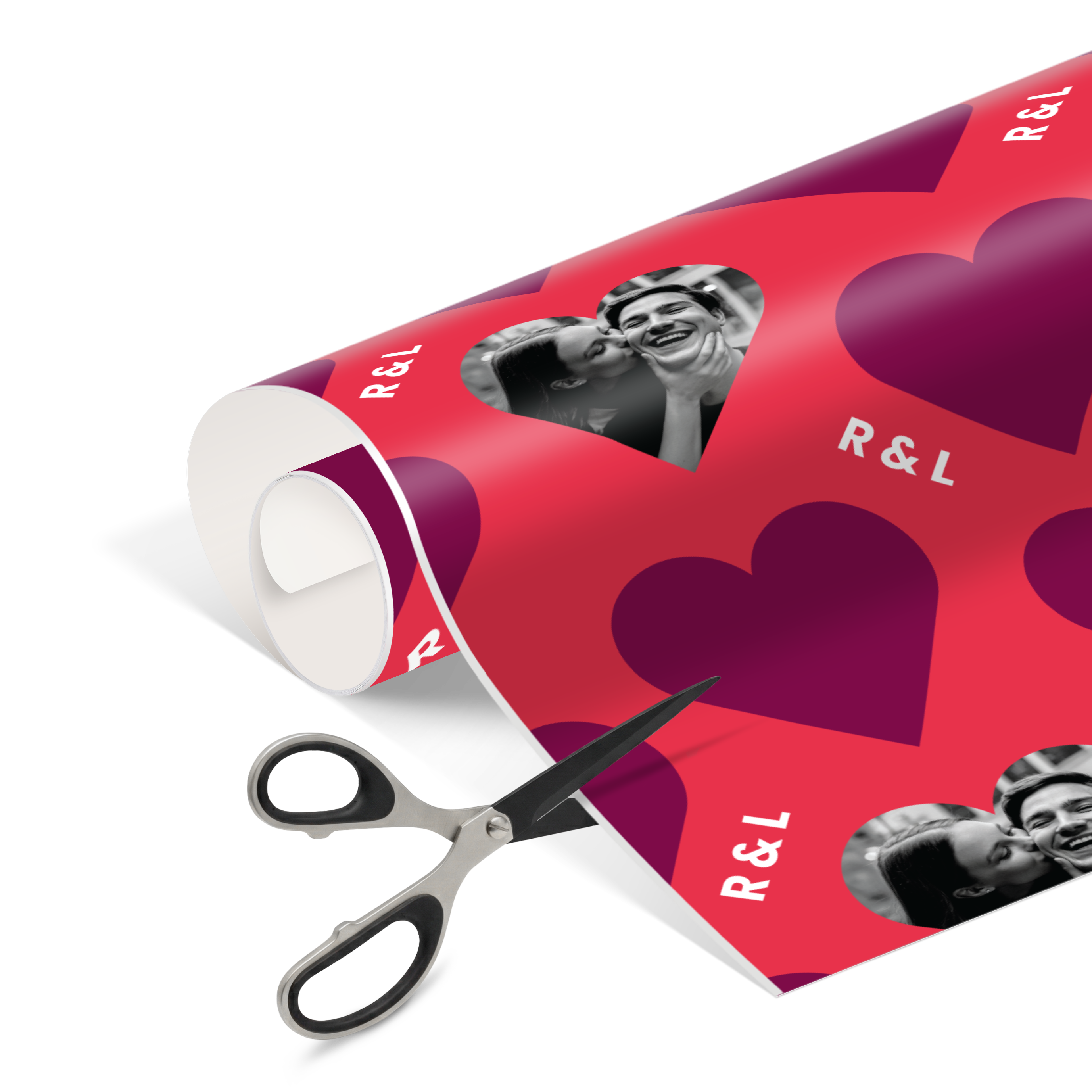 Geschenkpapier mit Foto selbst gestalten, rotes Design mit Herzen und persönlichen Initialen R&L. Bedruckt mit einem Foto eines küssenden Paares, wird es gerade mit einer Schere geschnitten.