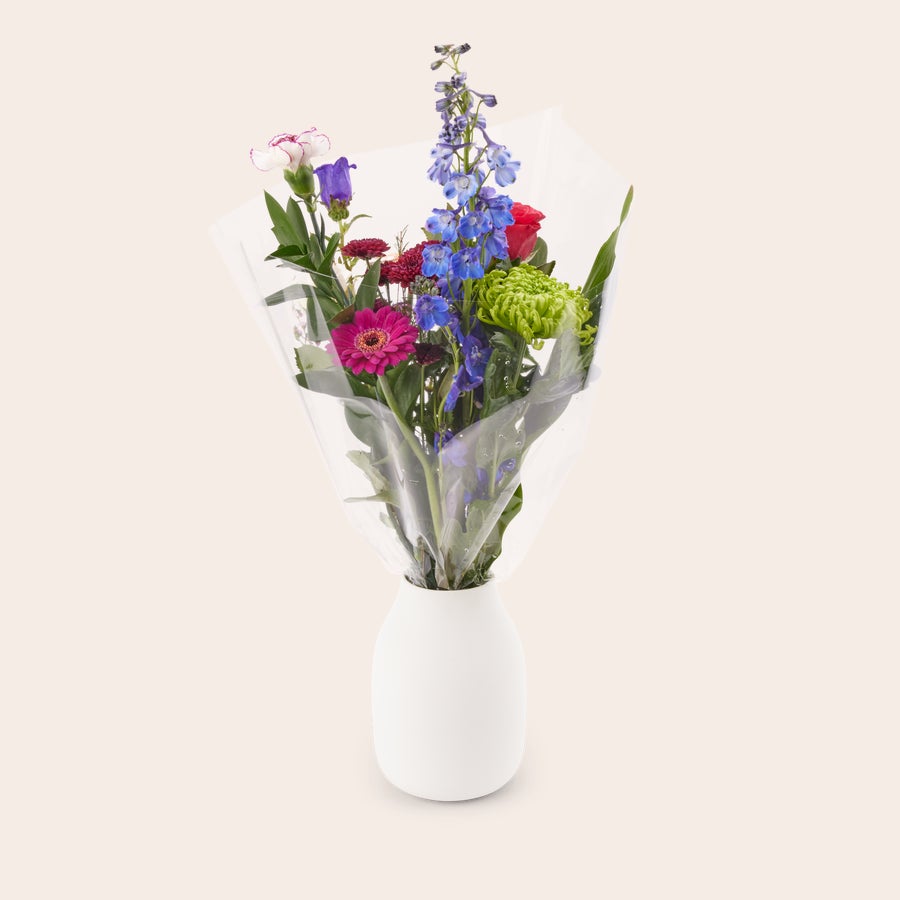 Bloemen - Natuurlijk plukboeket Een kleurrijk natuurlijk plukboeket met roze, blauwe en rode bloemen, verpakt in folie, met een gratis cadeaukaartje.