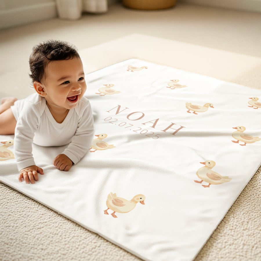 Copertina neonato personalizzabile Neonato sorridente su una coperta morbida personalizzata con stampa paperelle nome Noah e data 02.07.2025.