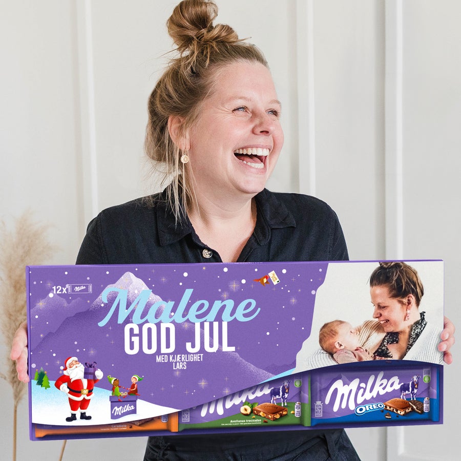 Giant personlig Milka-sjokolade Smilende kvinne holder en XXL personlig Milka sjokoladeplate - 12 barer, tilpasset med navn "Malene God Jul med kjærlighet Lars" og bilde.