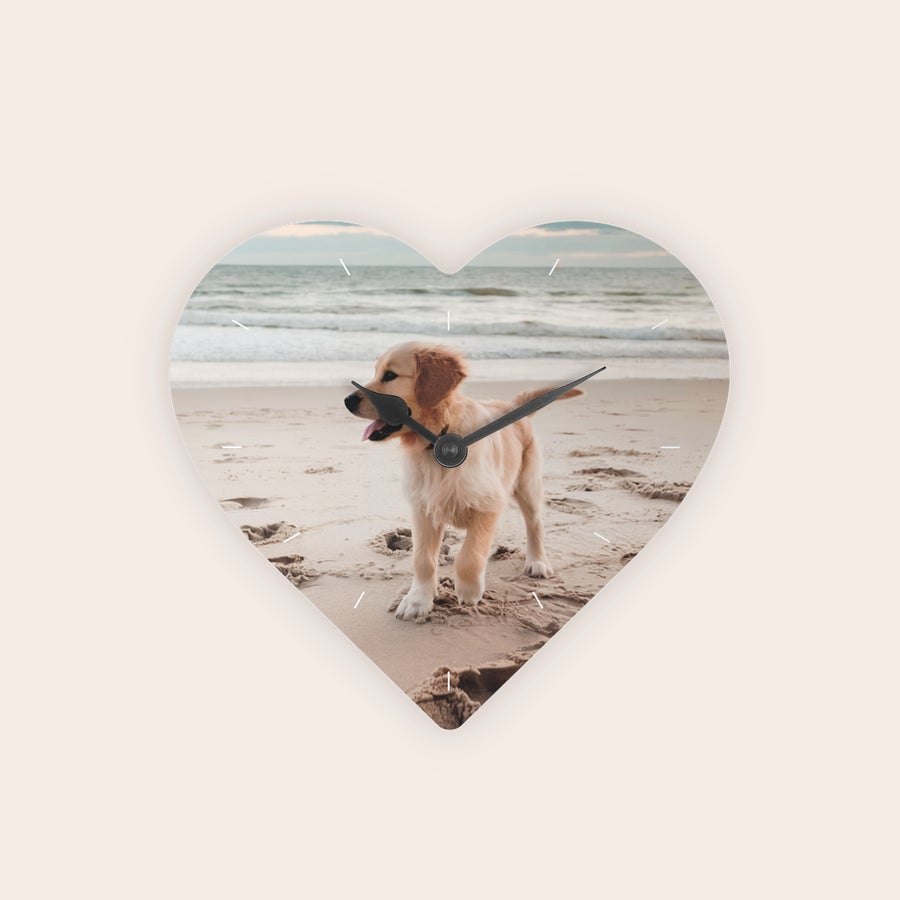 Wandklok bedrukken - Hartvormig Hartvormige wandklok bedrukt met een foto van een puppy op het strand, en zwarte wijzers voor een persoonlijke wandklok.