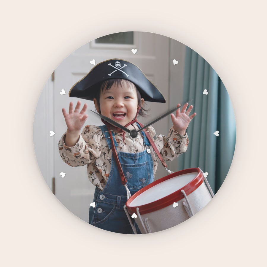 Ceas de perete personalizat Ceas rotund personalizat cu o fotografie a unui copil zâmbitor în costum de pirat, având inimioare albe ca marcaje orare.
