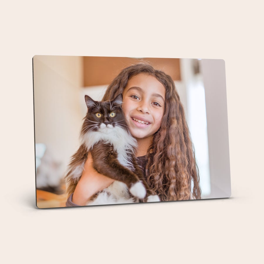 Impresión fotográfica con soporte Stand de fotos de hardboard con la foto de una niña sonriente abrazando un gato negro y blanco.
