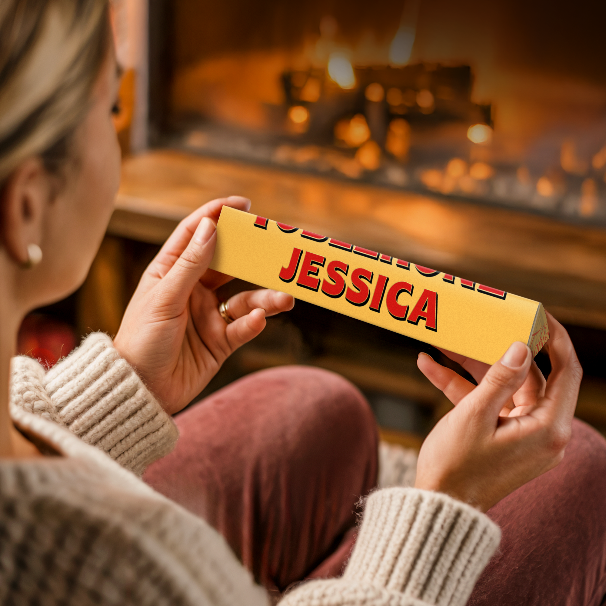 A woman holding a personalised Toblerone bar with Jessica printed in red on the custom yellow packaging