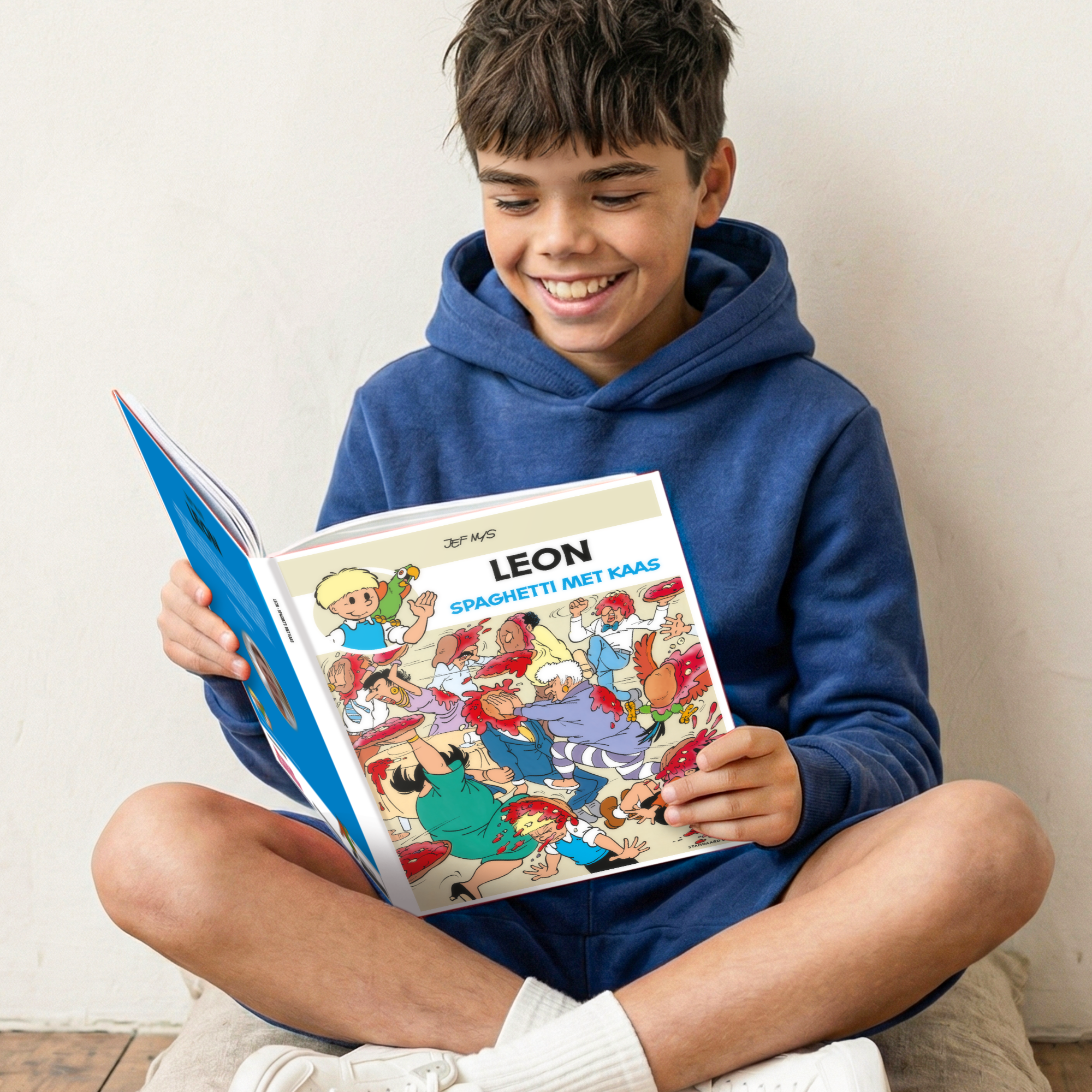 Lachende jongen leest gepersonaliseerd stripboek - Jommeke Spaghetti Met Kaas (Hardcover) met zijn naam LEON geprint op de voorkant.