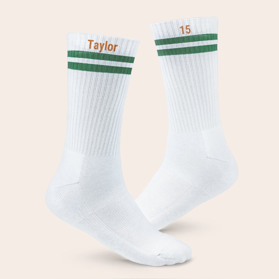 Calcetines deportivos con nombre Calcetines deportivos blancos con rayas verdes, estampados con nombre "Taylor" y número "15".