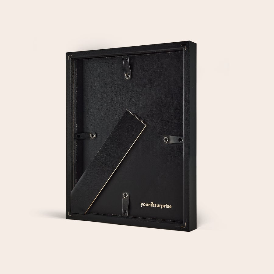 Personalised photo print with frame Back view of a personalized photo print with a black frame showing the stand and hanging hooks