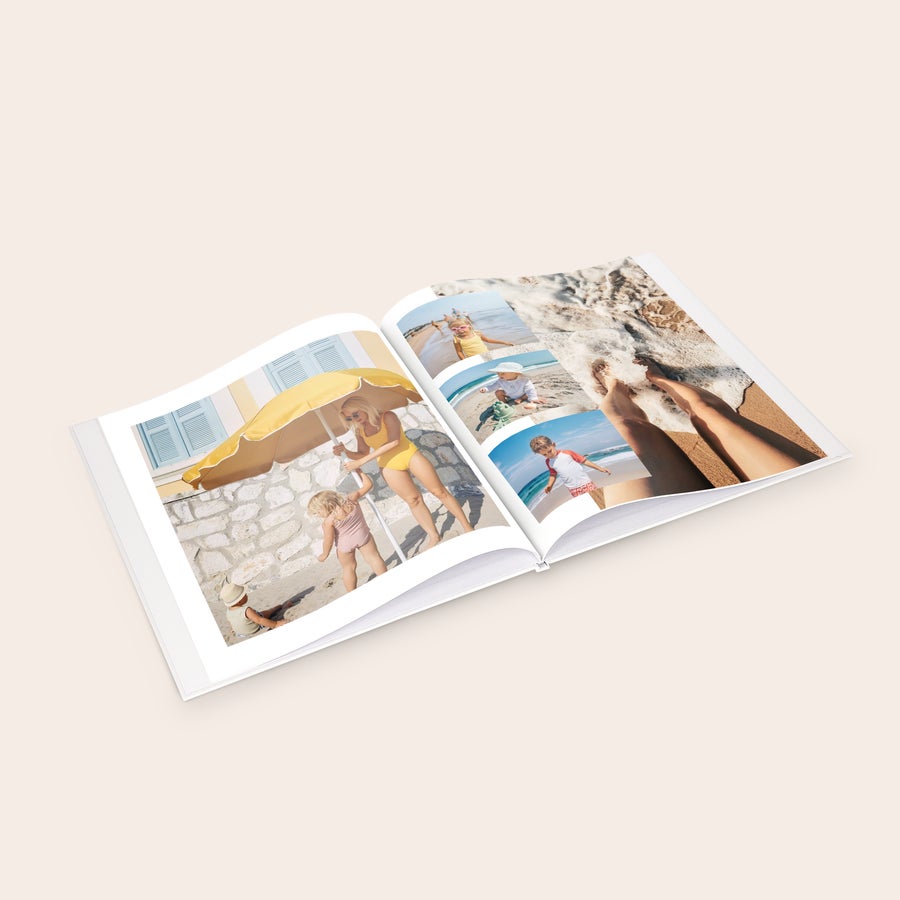 Osebni foto album Personaliziran foto album s trdo vezavo, odprt s tiskanimi fotografijami in besedilom po meri.