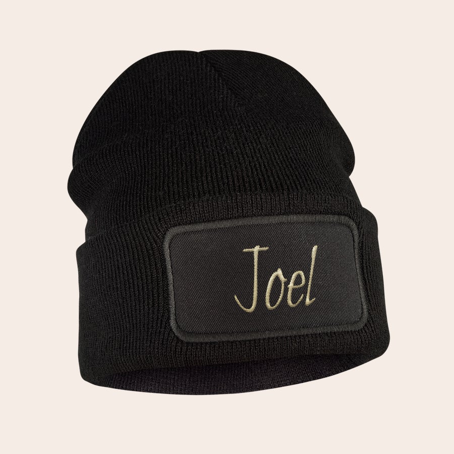 Chapéu bordado Gorro infantil preto de malha com o nome Joel bordado em bege para manter as orelhas aquecidas