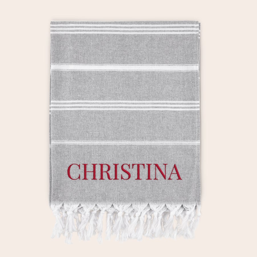 Toalha Hammam com nome Toalha de hammam personalizada cinza com listras brancas, bordada com o nome CHRISTINA em vermelho e franjas brancas. Traga o verão com sua própria toalha de hammam personalizada.