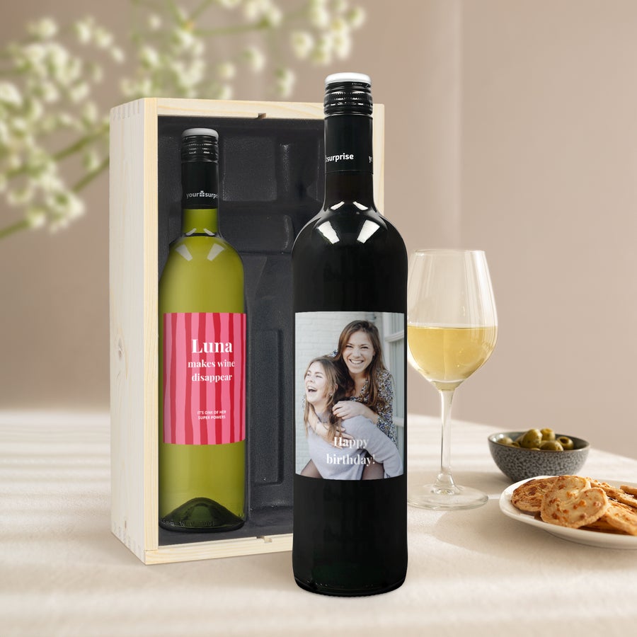 Confezione Vino Personalizzato Maison de la Surprise Confezione personalizzata di vino Maison de la Surprise, con due bottiglie: una di Sauvignon Blanc con etichetta rosa personalizzata e una di Merlot con foto.