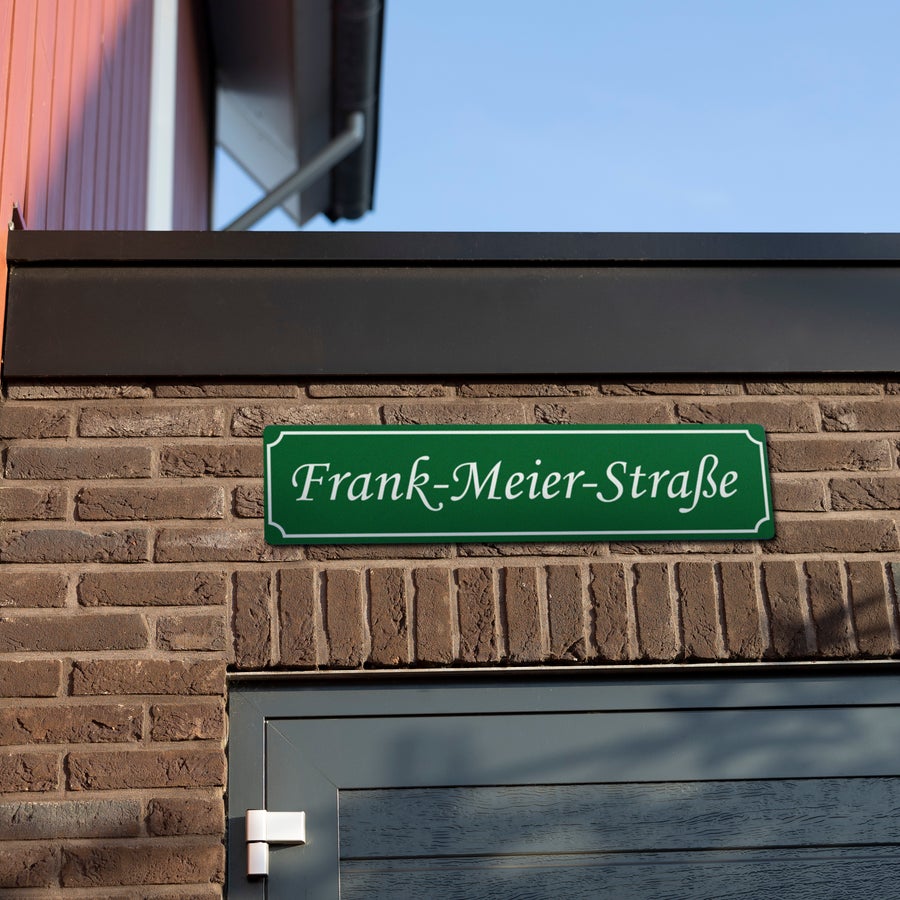 Straßenschilder selbst gestalten Grünes persönliches Straßenschild mit Frank-Meier-Straße bedruckt, an einer Ziegelwand montiert