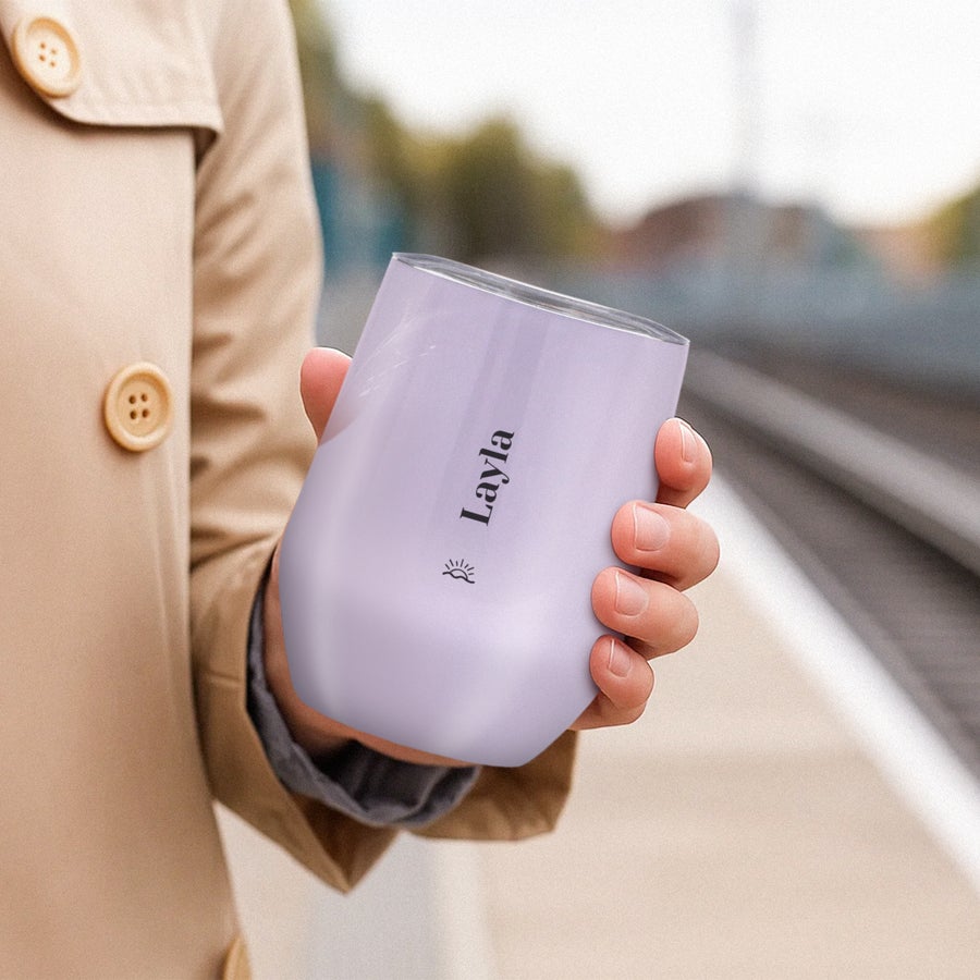 Tazza da viaggio con coperchio Mano che tiene una tazza da viaggio personalizzata viola con coperchio e il nome Layla stampato, per un'esperienza rinfrescante.