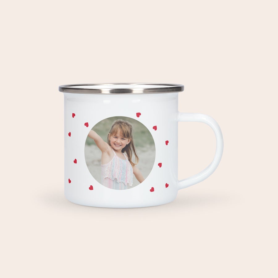 Cană personalizată din email Cană de smalț albă, personalizată prin imprimare cu fotografia unei fetițe zâmbitoare și inimioare roșii.