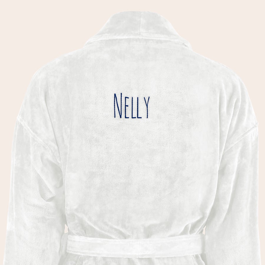 Badrock Dam med namn Mjuk vit badrock med namnet NELLY broderat i blått. Ge en personlig badrock broderad med egen text.