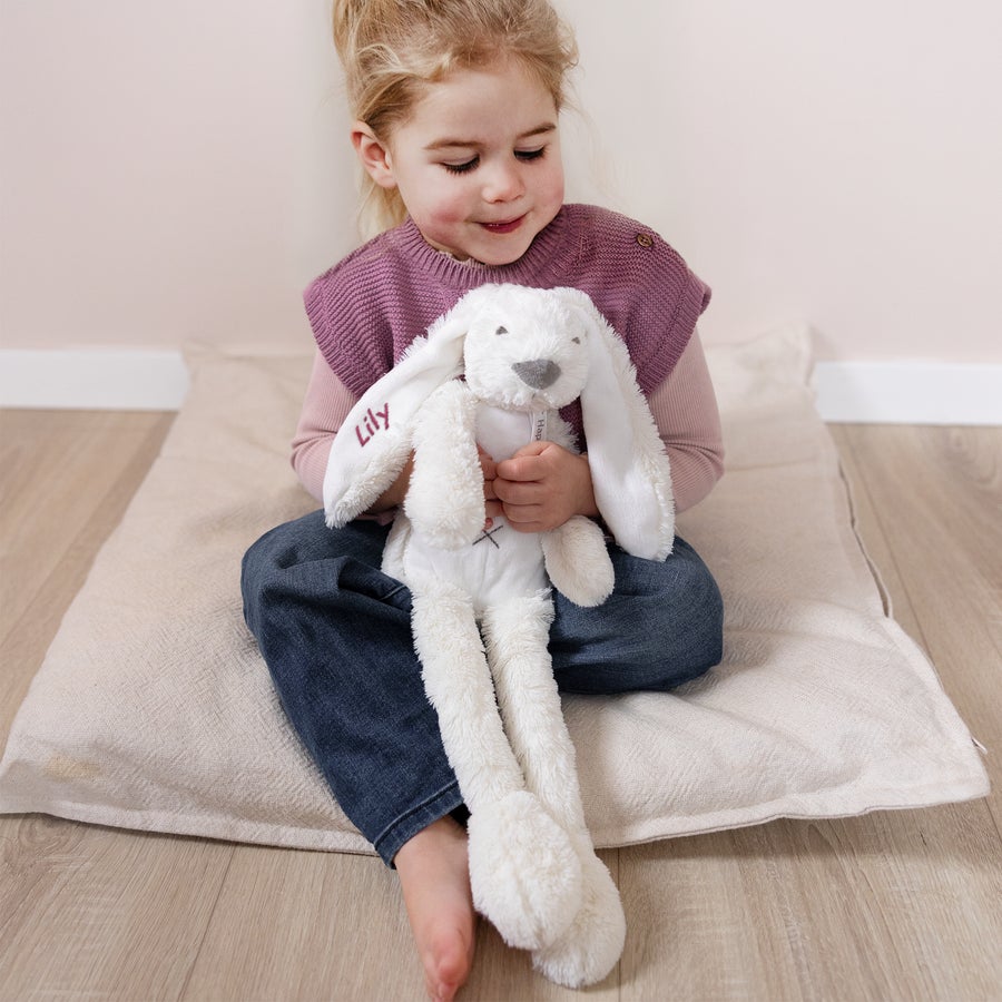 Peluche Coniglietto Personalizzato Bambina che abbraccia coniglietto peluche Richie bianco, ricamato con il nome personalizzato Lily in fucsia sull'orecchio